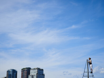 Canada, British Columbia, Vancouver, high-rise buildings, teenager on climbing frame - DISF002280