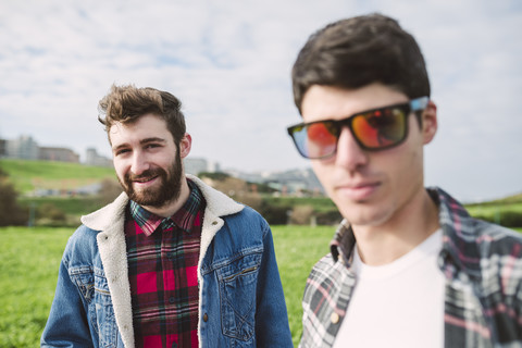 Portrait of smiling young man with his friend wearing mirrored sunglasses in the foreground stock photo