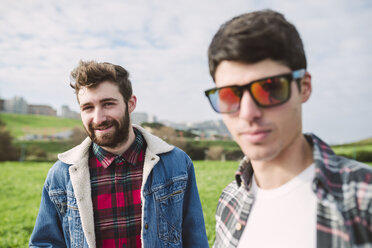 Portrait of smiling young man with his friend wearing mirrored sunglasses in the foreground - RAEF000719