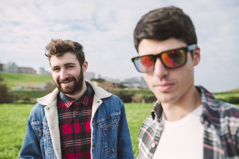 Porträt eines lächelnden jungen Mannes mit seinem Freund mit verspiegelter Sonnenbrille im Vordergrund - RAEF000719