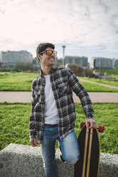 Lächelnder junger Mann mit Longboard und verspiegelter Sonnenbrille - RAEF000720