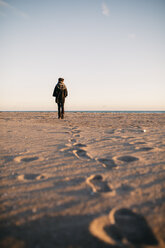 Rückenansicht einer jungen Frau am Strand im Winter - JRFF000236