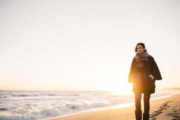 Junge Frau, die im Winter am Strand spazieren geht - JRFF000240