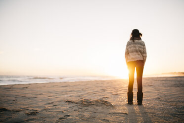 Rückenansicht einer jungen Frau, die im Winter am Strand steht - JRFF000242