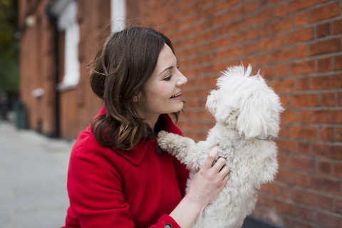 UK, London, lächelnde junge Frau von Angesicht zu Angesicht mit ihrem Hund, lizenzfreies Stockfoto