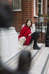 UK, London, young woman sitting on stairs besides her dog - MAUF000151
