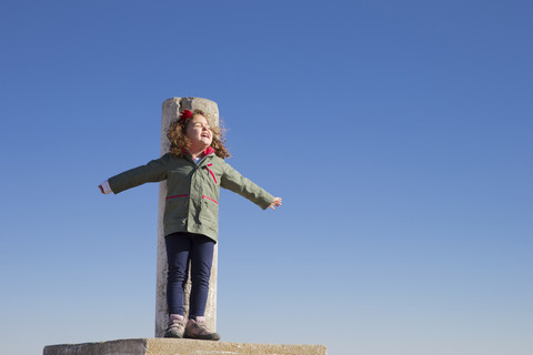 Spain, Consuegra, happy little girl standing on summit with arms outstretched stock photo