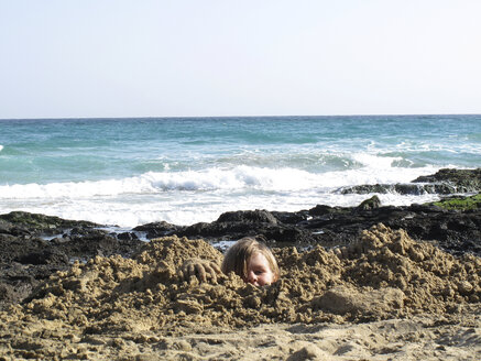 Spanien, Kanarische Inseln, Fuerteventura, Junge am Meer in Sand eingegraben - TMF000082