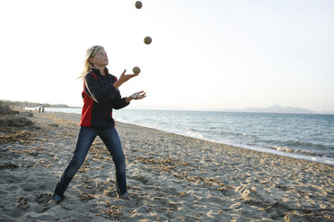 Spain, Majorca, boy juggling with three balls on the beach - TMF000086