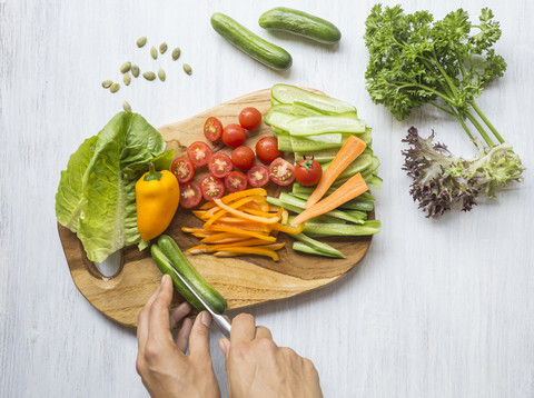 Woman's hands chopping vegetables on wooden board stock photo