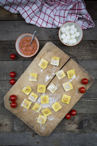 Hausgemachte Nudeln, Ravioli, gefüllt mit Tomaten-Mozzarella auf Schneidebrett, lizenzfreies Stockfoto