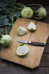 Organic kohlrabi on wood, knife on chopping board, halved - LVF004317