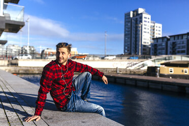 Ireland, Dublin, young man at city dock listening to music - BOYF000047