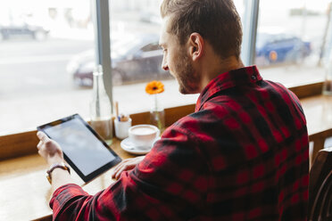 Mann in einem Café mit Blick auf eine digitale Tafel - BOYF000053