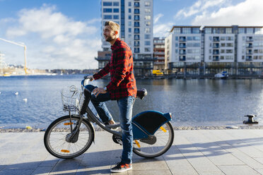 Ireland, Dublin, young man at city dock with city bike - BOYF000057