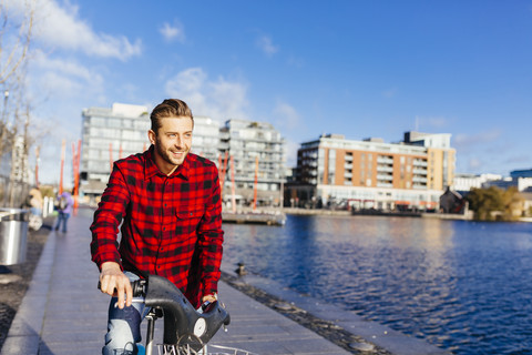 Ireland, Dublin, young man at city dock with city bike stock photo