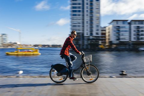 Ireland, Dublin, young man at city dock riding city bike stock photo