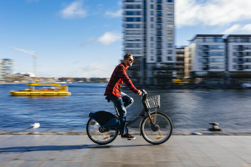 Ireland, Dublin, young man at city dock riding city bike - BOYF000060