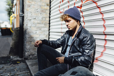 Young man leaning against roller shutter - BOYF000063