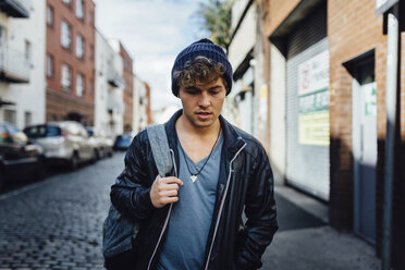 Ireland, Dublin, young man walking on the street with a backpack - BOYF000066