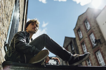 Ireland, Dublin, young man sitting on the ground of an alley - BOYF000067
