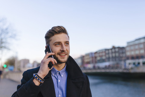 Irland, Dublin, Porträt eines jungen Geschäftsmannes, der mit einem Smartphone telefoniert, lizenzfreies Stockfoto