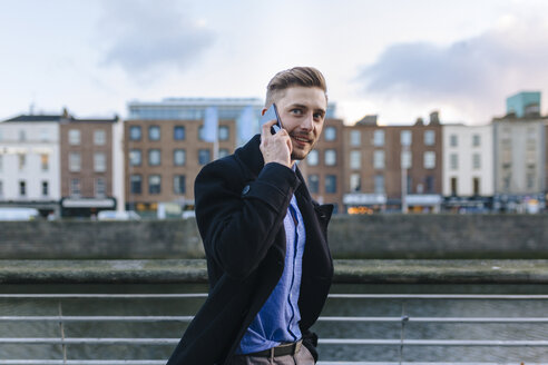 Ireland, Dublin, portrait of young businessman telephoning with smartphone - BOYF000083