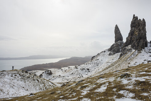 UK, Schottland, Isle of Skye, Junge fotografiert den schneebedeckten Old Man of Storr - JBF000252