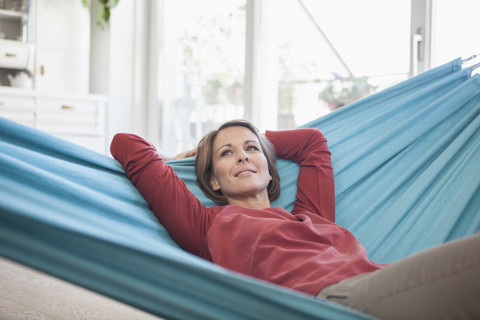 Lächelnde Frau zu Hause in der Hängematte liegend, lizenzfreies Stockfoto