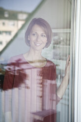 Smiling woman looking out of window - RBF003572