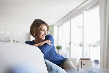 Smiling woman at home sitting on couch - RBF003575