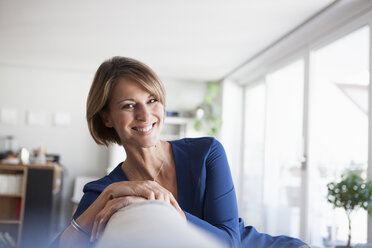 Portrait of smiling woman at home sitting on couch - RBF003577