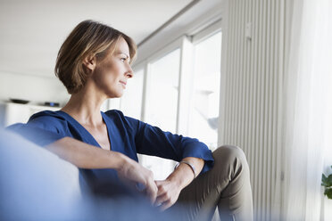 Woman at home sitting on couch thinking - RBF003586