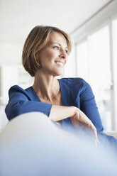 Smiling woman at home sitting on couch - RBF003588