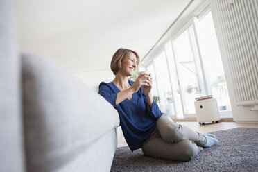 Relaxed woman at home leaning at couch - RBF003594