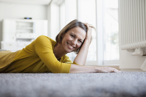 Porträt einer entspannten Frau zu Hause auf dem Boden liegend, lizenzfreies Stockfoto