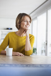 Entspannte Frau zu Hause mit einer Tasse Kaffee - RBF003619