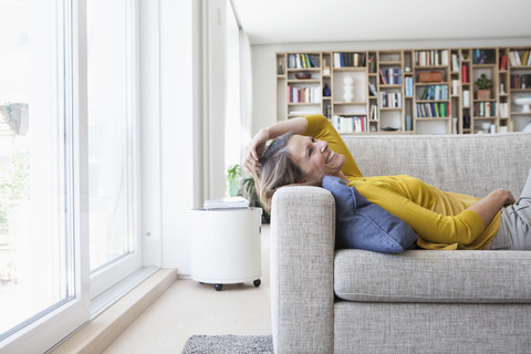 Happy woman at home lying on couch stock photo