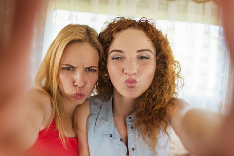 Porträt von zwei Freundinnen mit schmollenden Mündern, die in die Kamera schauen, lizenzfreies Stockfoto