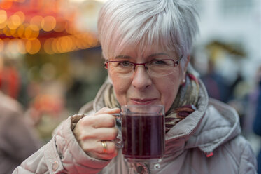 Ältere Frau hält ein Glas Glühwein - FRF000369