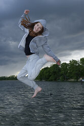 Girl jumping, lake in the background - LBF001312