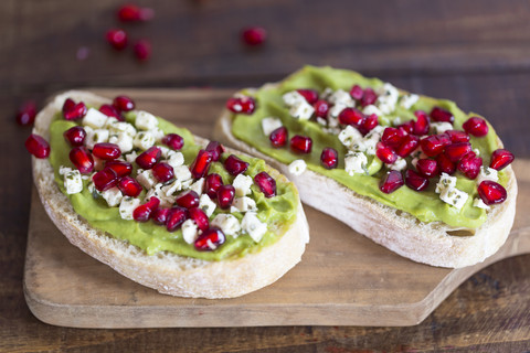 Zwei Baguettescheiben mit Avocadocreme, Fetakäse und Granatapfelkernen, lizenzfreies Stockfoto