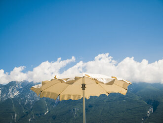 Italien, Gardasee, Sonnenschirm am Lido di Tignale, Monte Baldo im Hintergrund - GSF001058