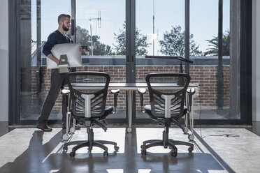 Man carrying computer monitor in empty office - ZEF007481