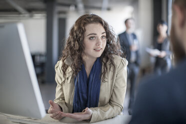 Young woman in office discussing with colleague - ZEF007514