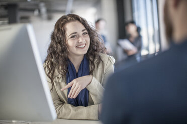 Young woman in office discussing with colleague - ZEF007515