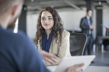 Young woman in office discussing with colleague - ZEF007516