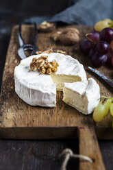 Holzbrett mit geschnittenem Camembert, Walnüssen und Trauben - SBDF002574