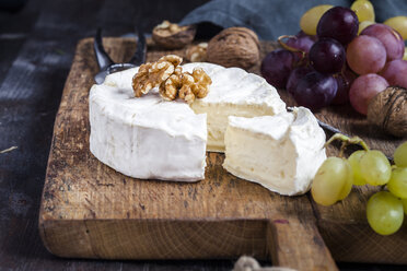 Wooden board with sliced camembert, walnuts and grapes - SBDF002575
