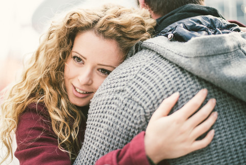 Porträt einer lächelnden jungen Frau, die ihren Freund umarmt, lizenzfreies Stockfoto